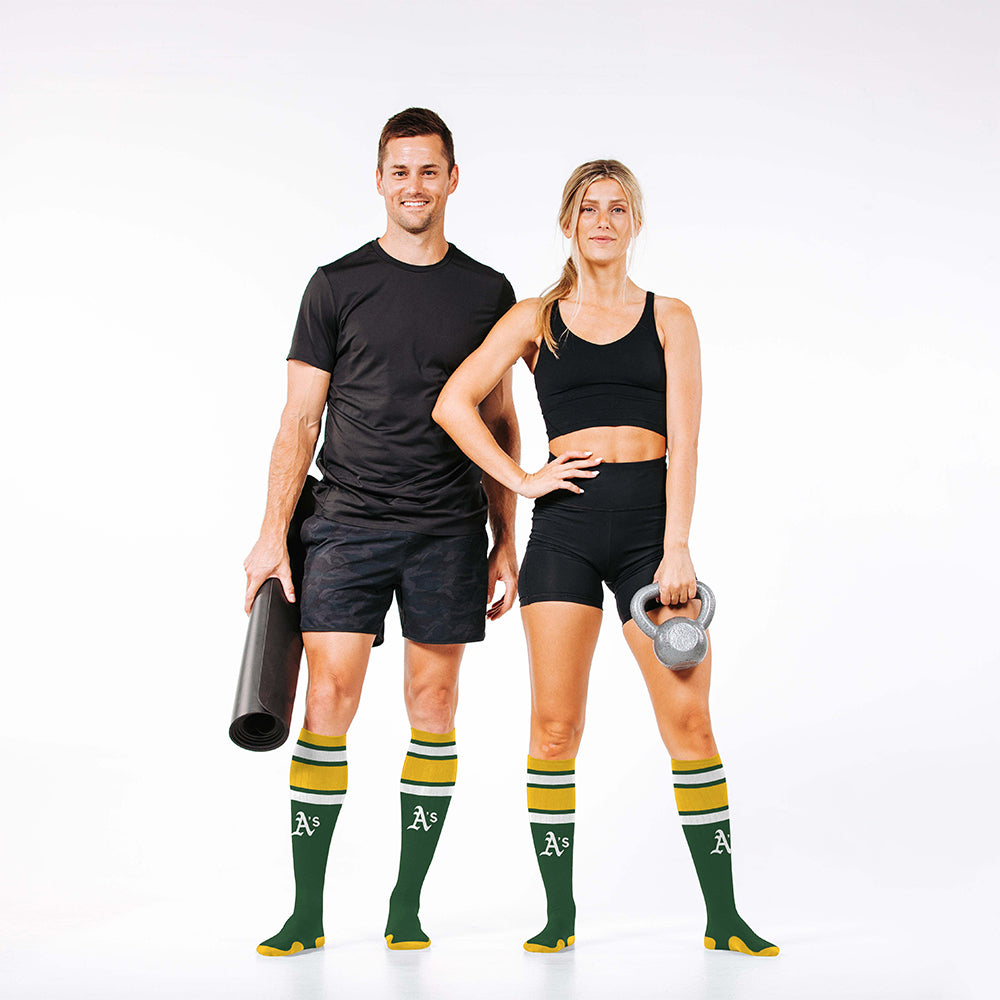 Man and woman wearing PRO Compression Major League Baseball Knee High Compression Sock Genuine MLB Merchandise Sock Oakland Athletics