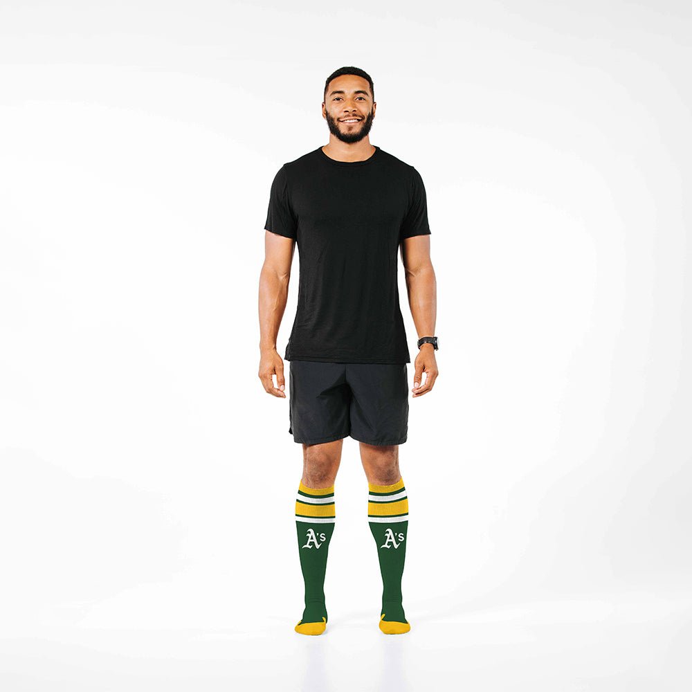 Man wearing PRO Compression Major League Baseball Knee High Compression Sock Genuine MLB Merchandise Sock Oakland Athletics