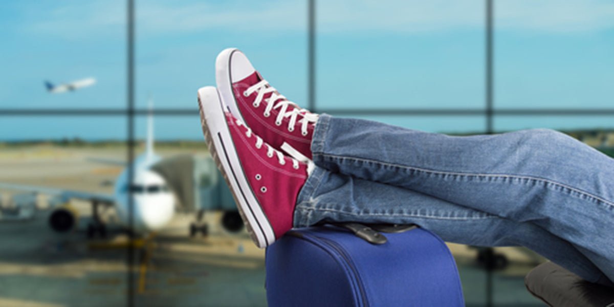 Feet kicked up on suitcase wearing compression socks ready to board a flight and travel.
