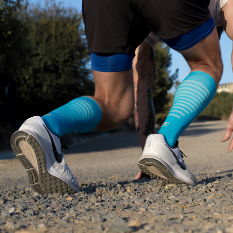 Male athlete sprinting wearing PRO Compression knee-high Elite socks in light blue.