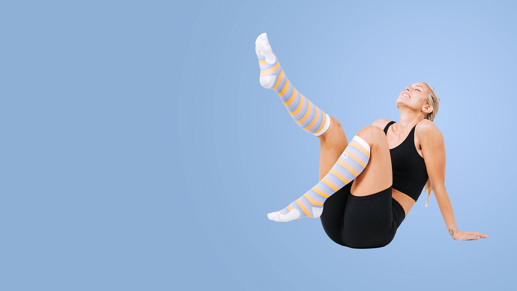 Athletic woman in black training outfit wearing colorful knee-high compression socks by PRO Compression.