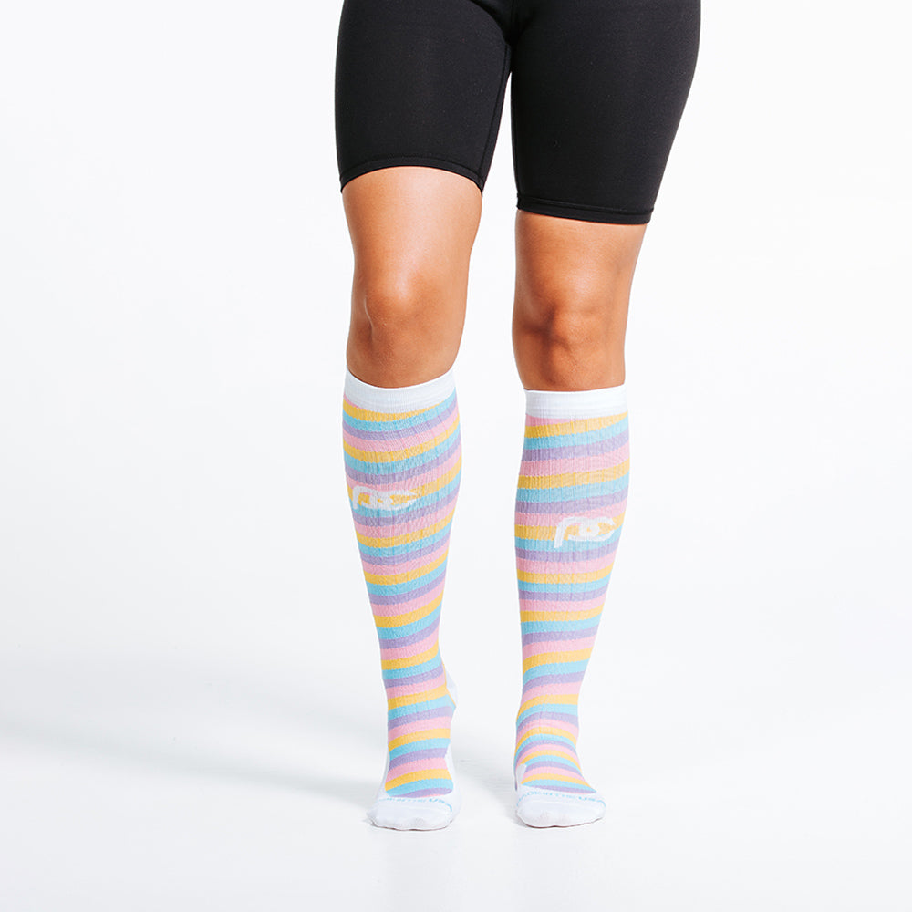 Marathon knee high compression socks with brightly colored stripes in blue, purple, pink ,and yellow - on model close up on feet