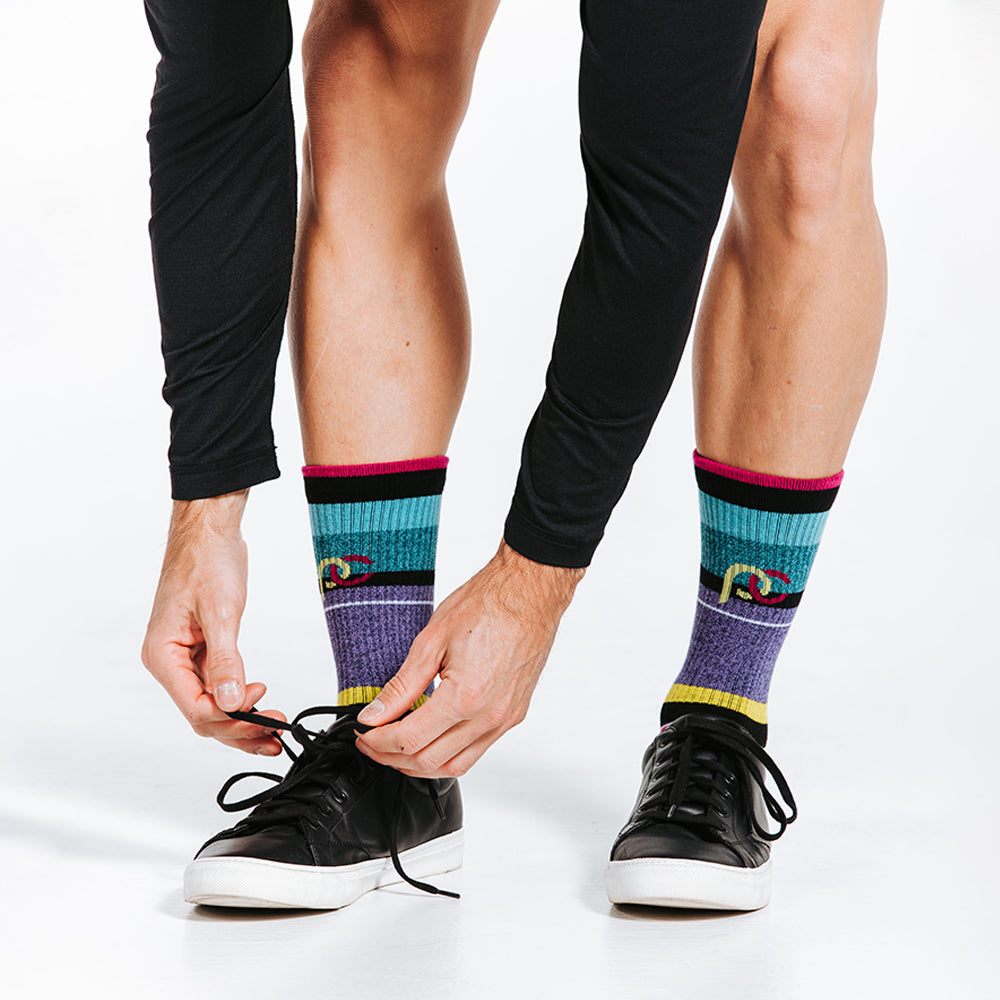 Striped colorful crew socks woven with lightweight compression for relaxed days - on model tying shoes