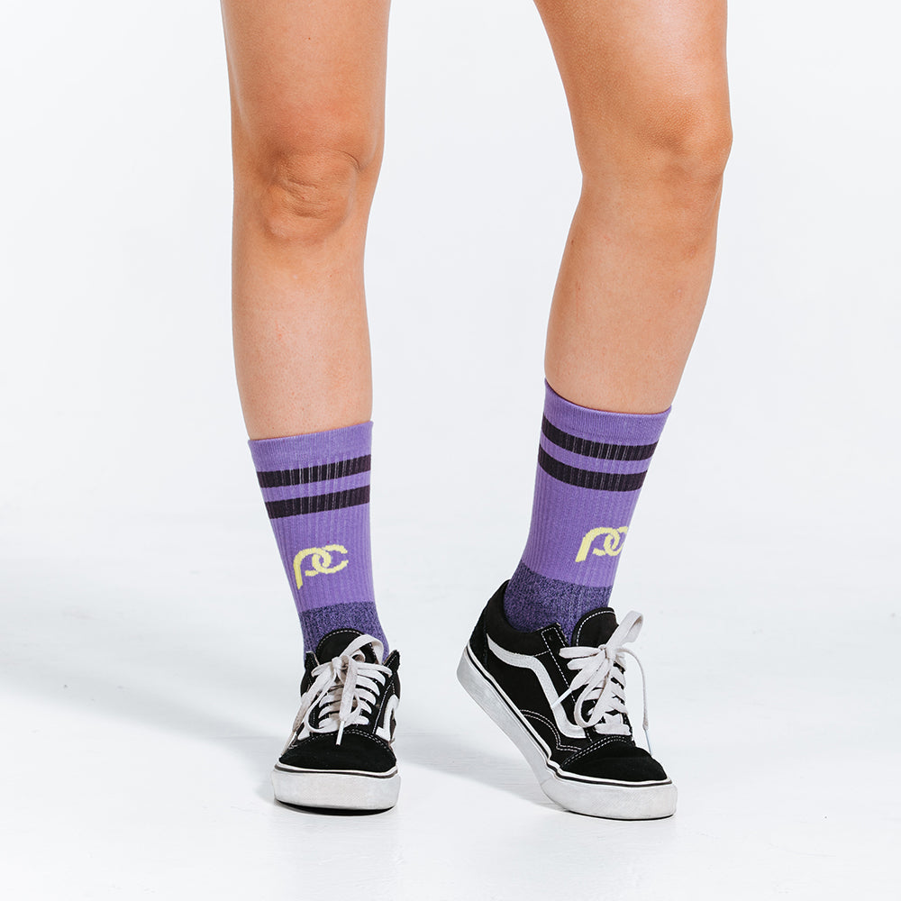 Purple socks with gold details, made with lightweight graduated compression - close up of model feet