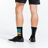 Crew length black compression socks with colorful accents and gold toes - close up of feet from rear