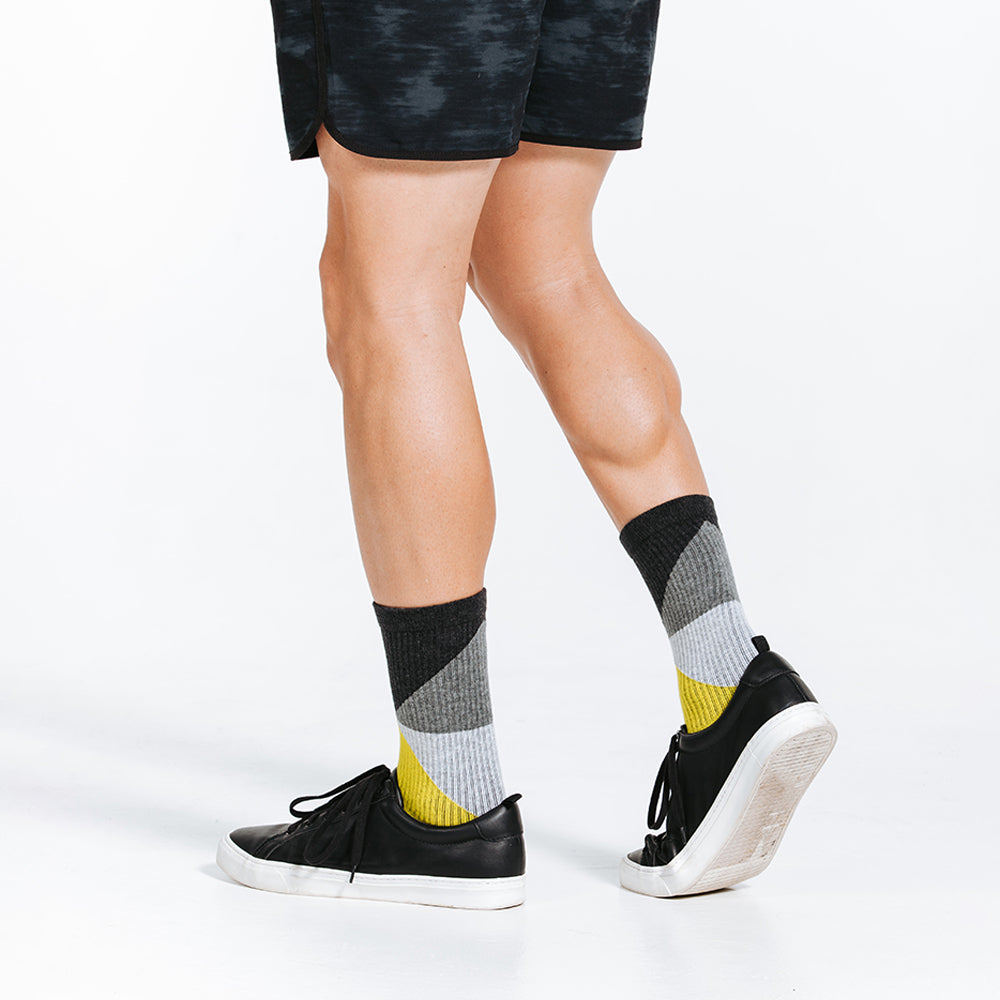 Black, grey, and yellow crew length compression socks - model walking close up on feet