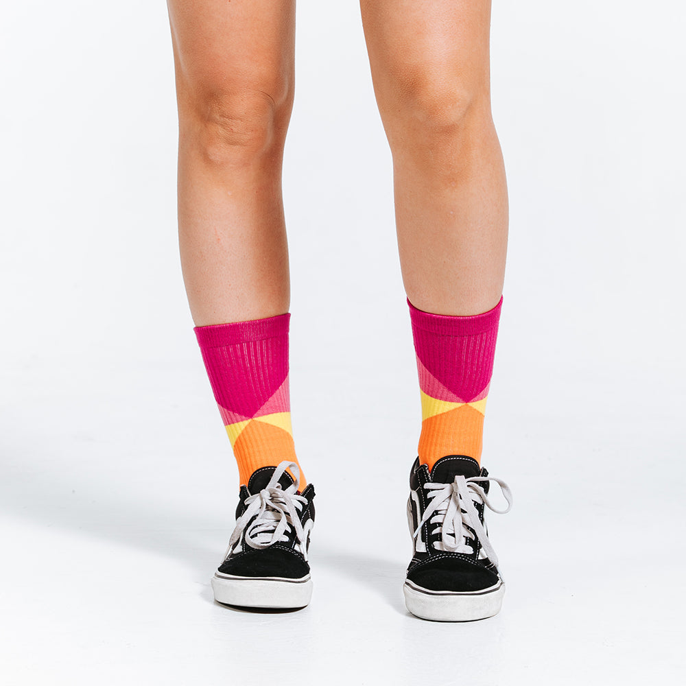 Colorful compression socks, crew length, with pink, yellow, orange, and red - close up of feet
