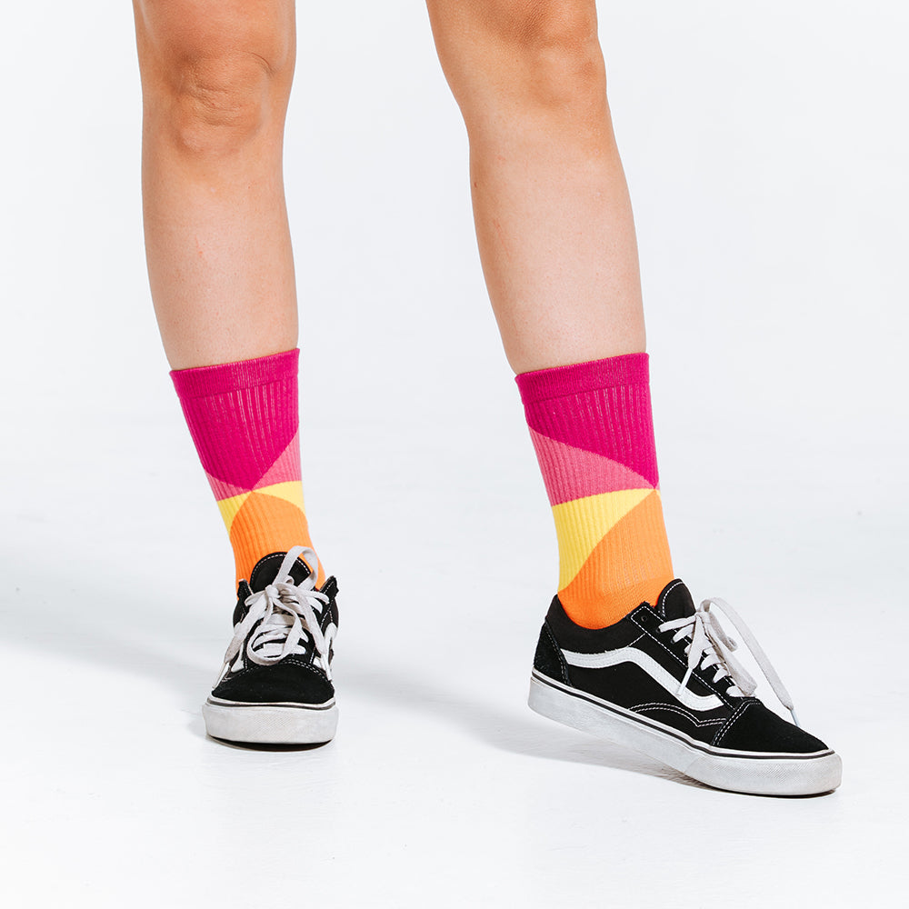 Colorful compression socks, crew length, with pink, yellow, orange, and red - close up of feet, angle 2