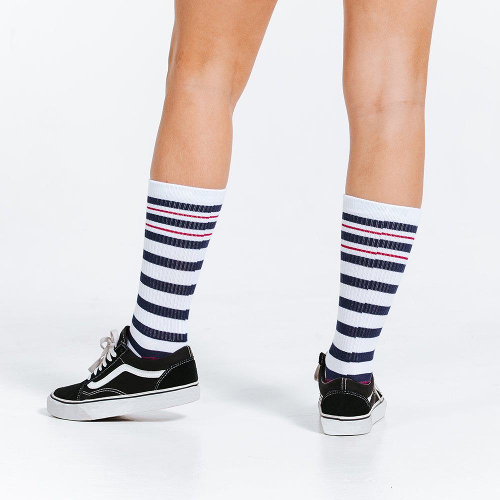 Blue, pink, and white striped crew length compression socks - close up on feet rear view